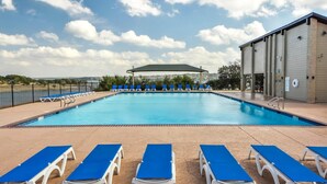 Une piscine avec des chaises longues bleues et un espace abrité.