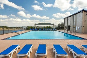 Une piscine avec des chaises longues bleues et un espace abrité.