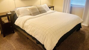 A hotel room with a bed, two bedside lamps, a nightstand, a painting on the wall, and a window with blinds. - Lake Travis Views, King Bed, Two Sunset Decks on the Golf Course (Point Venture)