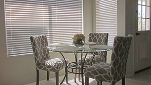 A dining area with a round glass table and four patterned chairs.