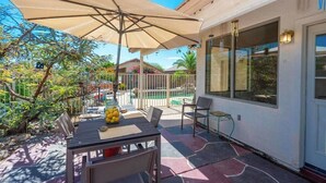 A patio with a table, chairs, and an umbrella.