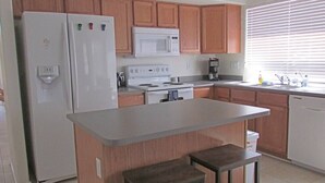 A kitchen with wooden cabinets, a white refrigerator, a microwave, a stove, and a dishwasher.