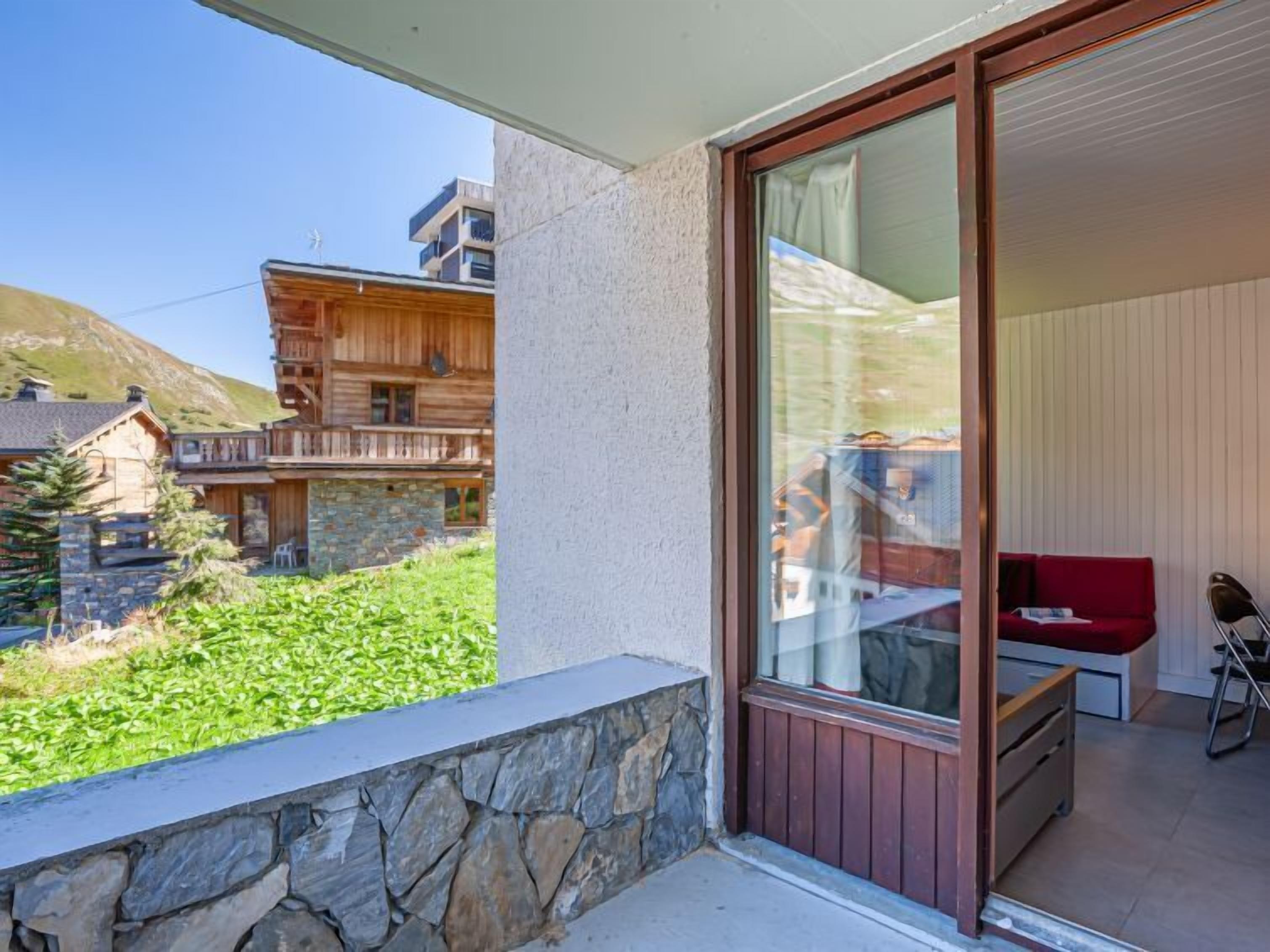 A balcony with a stone wall, a red sofa, and a wooden deck.