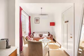 Una habitación de hotel con cama, escritorio, silla, mesita de noche y ventana con cortinas.