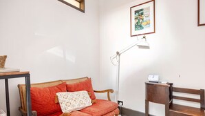 A room with a wooden sofa, a small table, a floor lamp, and a framed picture on the wall. - William Arnott Boutique Hotel (Morpeth)