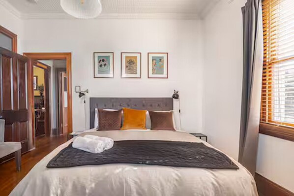 Un dormitorio con una cama, una mesita de noche y una ventana con persianas.