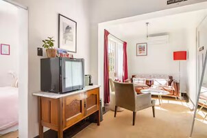 Una habitación con un armario de madera, una televisión, una cama, un sofá y una lámpara roja.