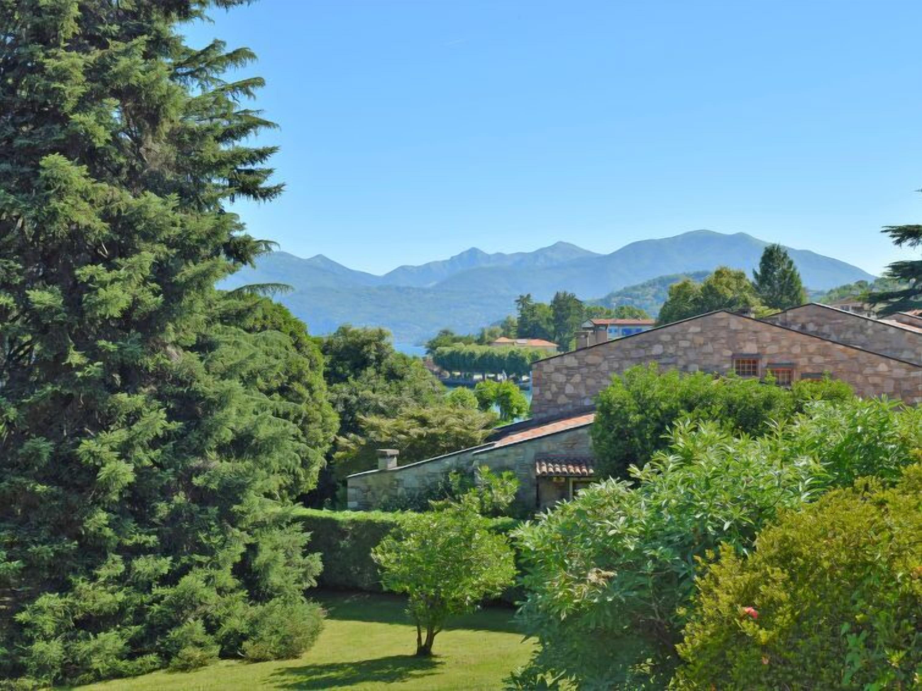 A stone building with a garden and mountains in the background.