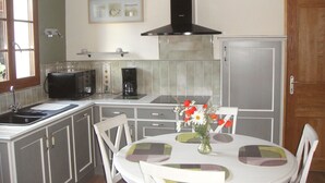 A compact kitchen with a sink, microwave, coffee maker, and a dining table with chairs. - House with courtyard on south-facing beach 10 kms away (Nibas)
