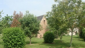 A brick building with a sloped roof, surrounded by well-maintained grass and various trees. - House with courtyard on south-facing beach 10 kms away (Nibas)