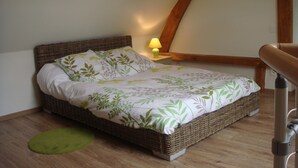 A single bed with a leaf-patterned bedspread, a bedside lamp, and a wooden headboard in a room with wooden flooring and a sloped ceiling. - House with courtyard on south-facing beach 10 kms away (Nibas)
