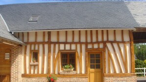 A half-timbered building with a brick base and white wooden beams, a wooden door, and two windows with flower boxes. - House with courtyard on south-facing beach 10 kms away (Nibas)