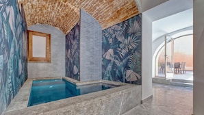 Una piscina con pared de azulejos, ventana con marco de madera y vista al exterior.