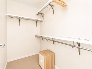 Une pièce avec un meuble en bois, une étagère en métal et un mur blanc.