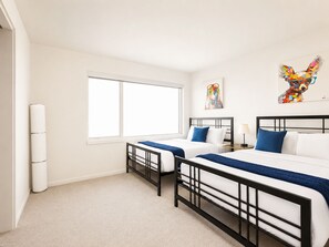 Une chambre d’hôtel avec deux lits, une grande fenêtre et des œuvres d’art accrochées au mur.