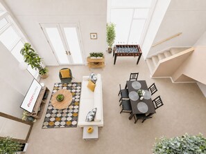 Un vaste espace de vie comprenant un canapé, une table basse et une table à manger, un escalier et une vue sur le ciel.