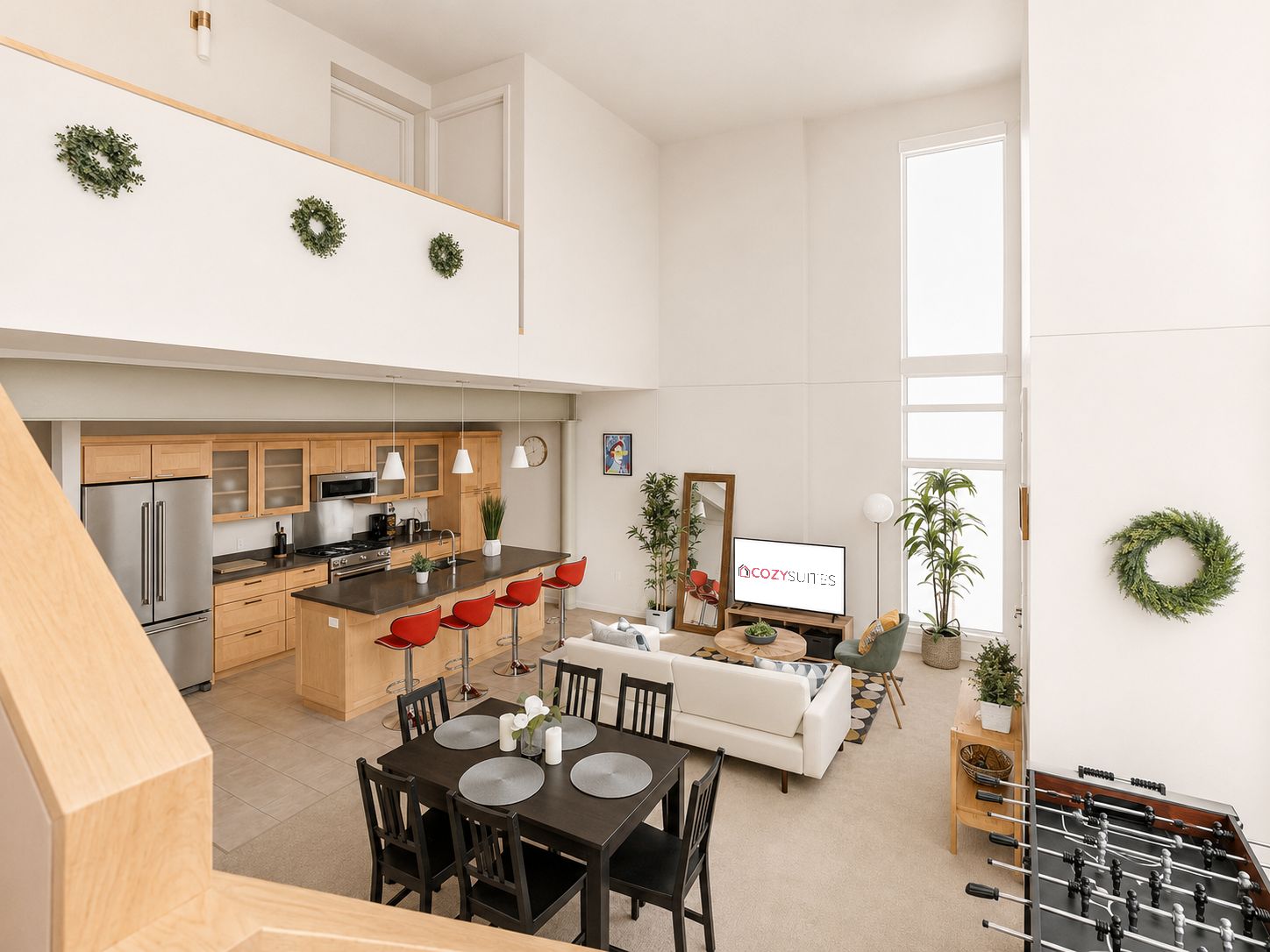 Une cuisine moderne avec un îlot central, un coin repas comprenant une table et des chaises, un canapé et une table de baby-foot.