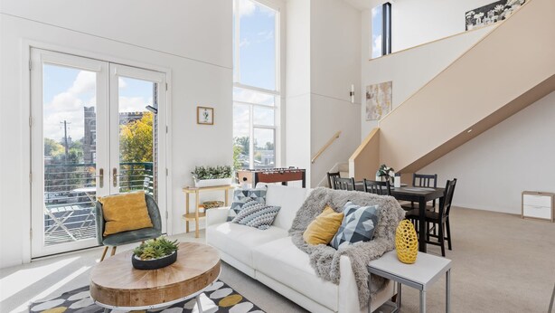 Ein modernes Wohnzimmer mit einem weißen Sofa, einem Couchtisch und einer Treppe.