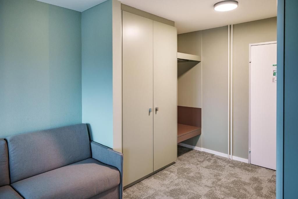 Una stanza con un divano, un armadio, una porta e un pavimento rivestito di moquette.