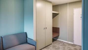 Ein Zimmer mit einer Couch, einem Schrank, einer Tür und einem Teppichboden.