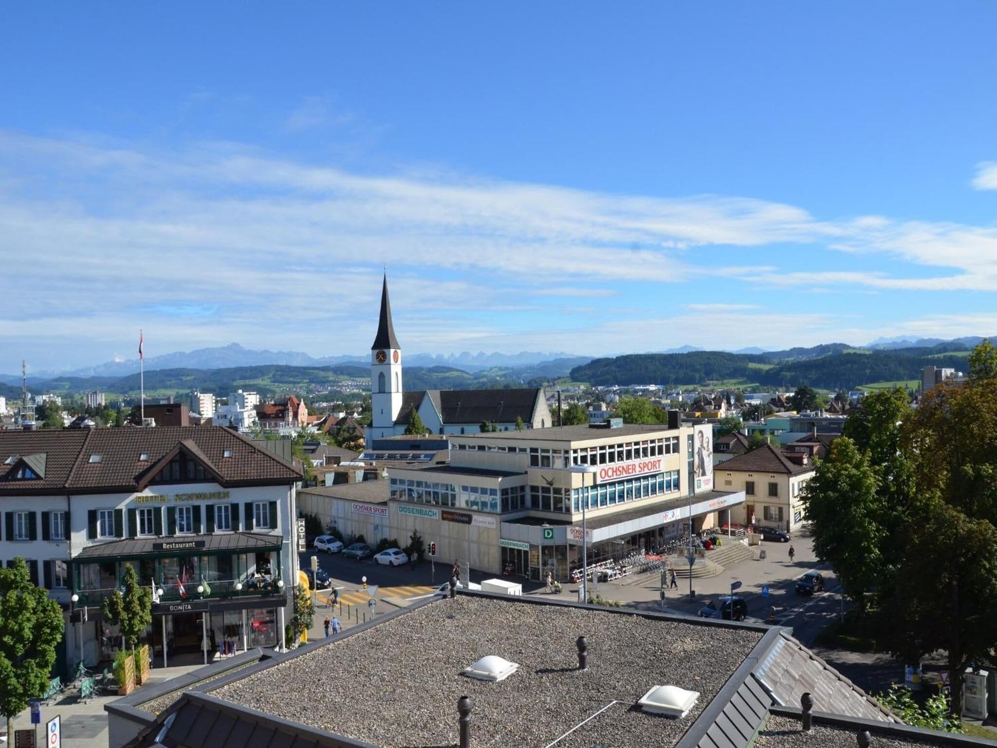 A town with a prominent church tower, a sports center, and a restaurant.