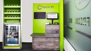 A check-in area with a green wall, a digital display, and a cashbox. -  flexy.motel Wil (Wil)