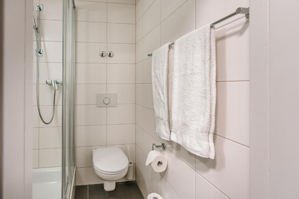 A bathroom with a glass-enclosed shower, a toilet, and a towel rack with a towel.