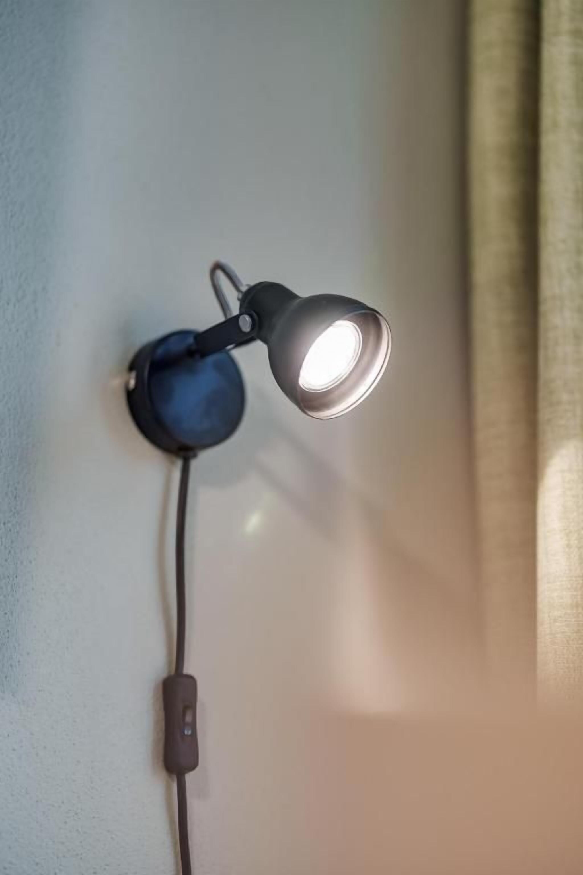 A wall-mounted lamp with a cord plugged into a power outlet.