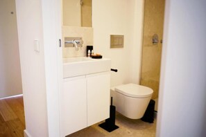 Une salle de bain avec un lavabo blanc, des toilettes et un espace douche.