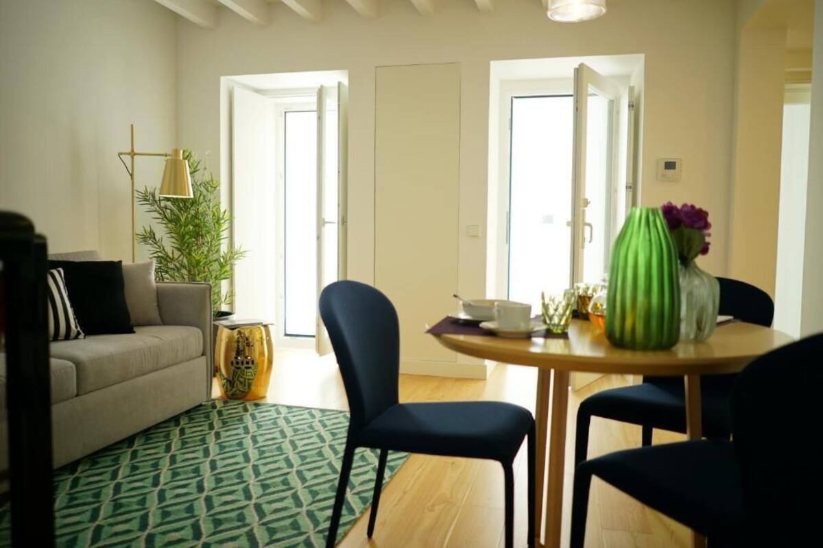 Una sala de estar con un sofá, dos sillones, una mesa de centro y un tapete verde estampado.