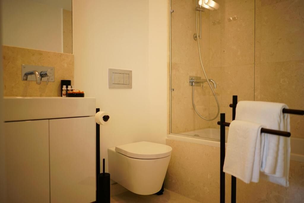 A modern bathroom with a toilet, shower, and towel rack.