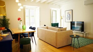 A modern living room with a sofa, a dining table, and a TV. - Casas da Baixa - Vila Intendente (Lisbon)