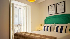 A bedroom with a large bed, a green headboard, and two framed artworks on the wall. - Casas da Baixa - Vila Intendente (Lisbon)