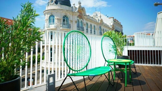 A balcony with two green chairs and a potted plant, overlooking a historic building with a dome. - Casas da Baixa - Vila Intendente (Lisbon)