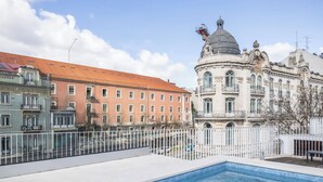 A pool area with a view of a historic building with ornate architecture and a dome. - Casas da Baixa - Vila Intendente (Lisbon)