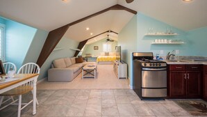 Een gezellige loft met woonruimte, een keuken, een eethoek en een slaapkamer met een bed en bureau.