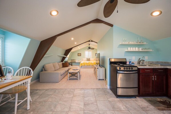 A cozy loft-style living space with a kitchen, dining area, and a bedroom with a bed and a desk.