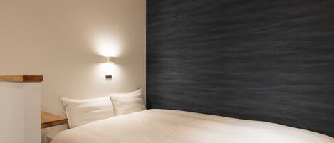 A bedroom with a bed, a nightstand, a wall-mounted air conditioner, and a wall light.