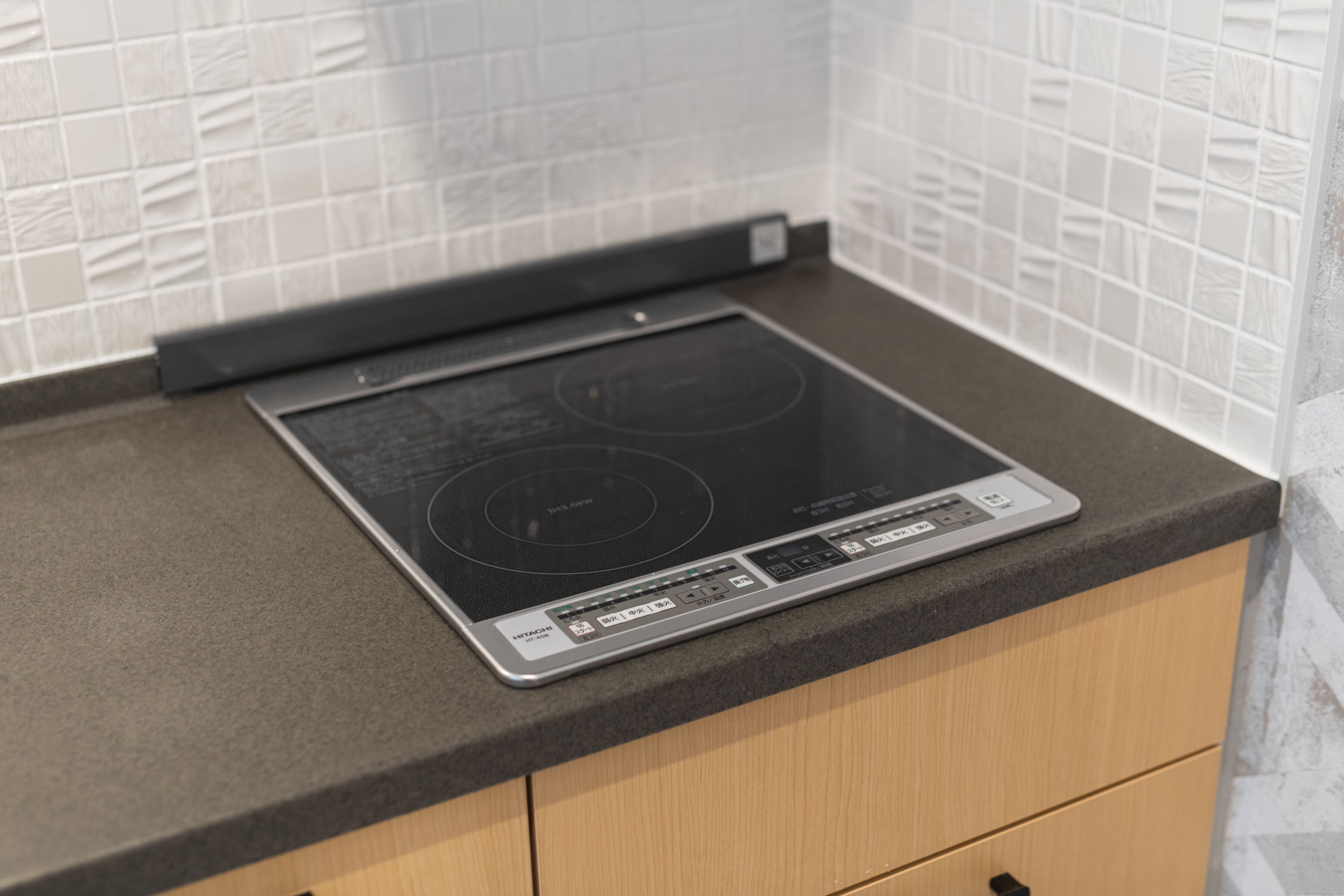 A kitchen with a built-in induction cooktop and a black countertop.