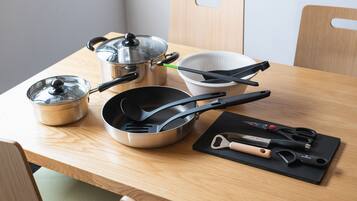 A kitchen counter with stainless steel cookware, a colander, and a cutting board with utensils.