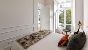 Een slaapkamer met een groot bed, een vacht plaid en uitzicht op buiten.