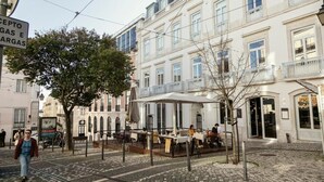 Een geplaveid straatje met terrasjes van een café, omgeven door historische gebouwen.
