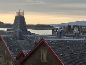 A building with a steeply pitched roof, a prominent chimney, and a red-brick facade. - The Coorie Inviting 1-bed Apartment in Oban (Oban)