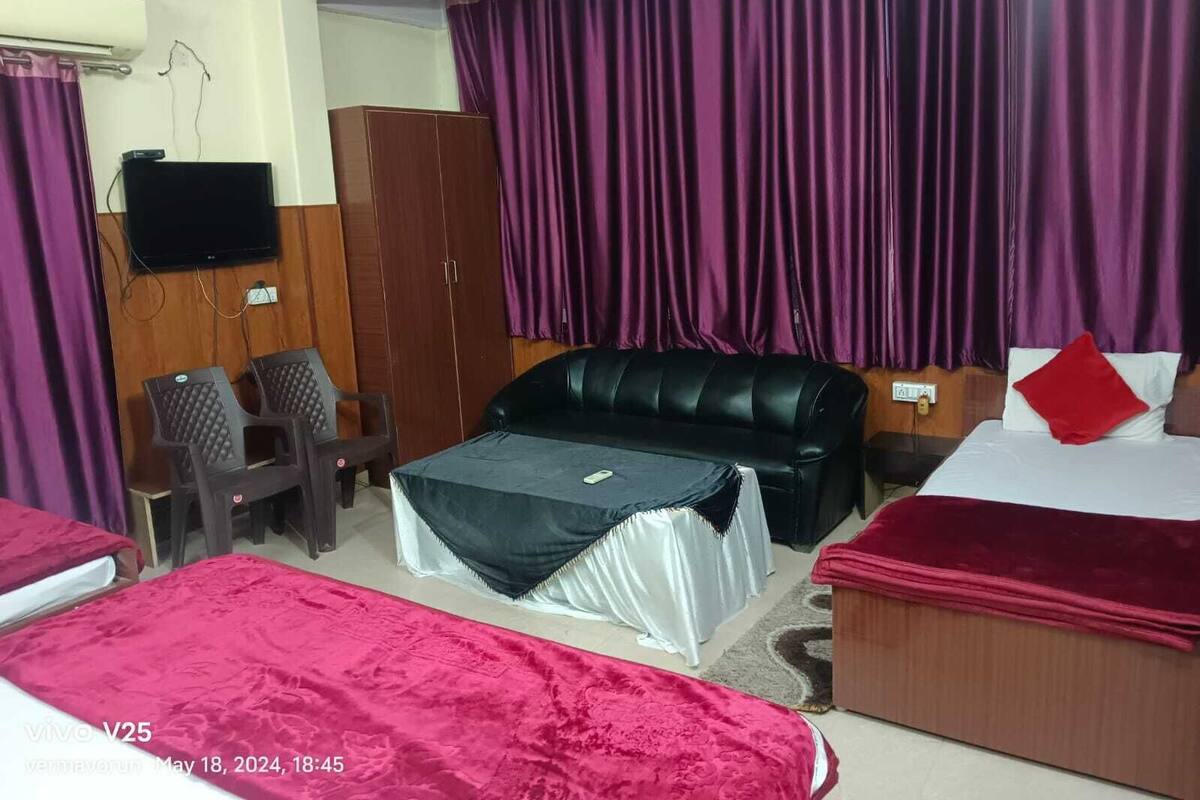 A hotel room with two beds, a sofa, a TV, and a wardrobe.