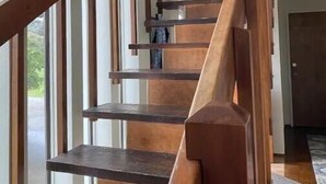 A wooden staircase with a handrail leading to a landing.