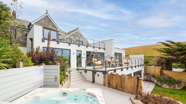 Een modern huis met een hottub, buitenmeubilair en uitzicht op het landschap.
