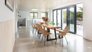 Een moderne eetruimte met een houten tafel en stoelen, grote ramen en uitzicht op het omliggende landschap.