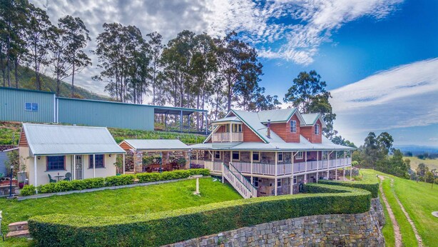 A large, two-story house with a stone foundation, a covered porch, and a stone wall surrounding the property. - Bimbadeen Mountain House - Valley views abound from this unique stone home (Mount View)