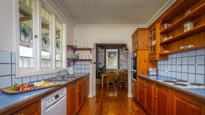 A kitchen with wooden cabinets, a dishwasher, and a tiled backsplash. - Bimbadeen Mountain House - Valley views abound from this unique stone home (Mount View)