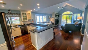 A spacious kitchen with a large island, wooden flooring, and a dining area with a couch. - F39 Classy Bretton condo with AC, wifi, mountain views, updated bathrooms right on the golf course! (Bretton Woods)